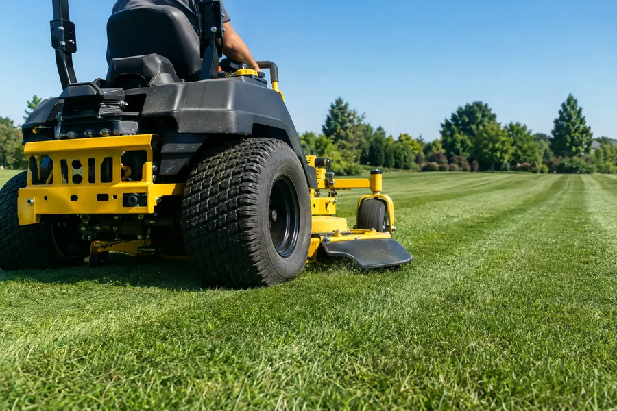 Zero-turn mower cutting stripes into a green lawn